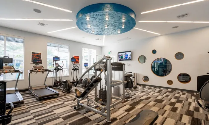 The Franklin Delray apartments' gym with a variety of exercise equipment and weights.