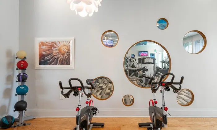 Fitness center at our apartments for rent in Delray Beach, Florida, featuring two spin bikes and circular mirrors.