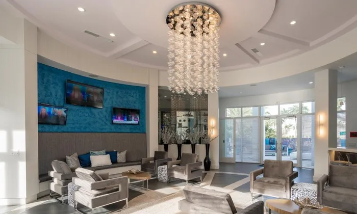 Resident lounge at our apartments for rent in Delray Beach, featuring cushioned chairs and a hanging chandelier.
