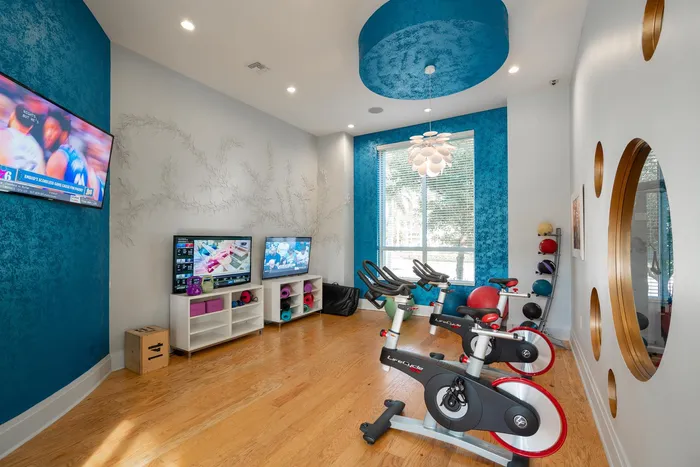 Fitness center at our apartments for rent in Delray Beach, Florida, featuring two spin bikes and two TVs.