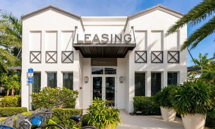 The leasing office at our apartments for rent in Delray Beach, featuring a view of the entrance and white building exterior.