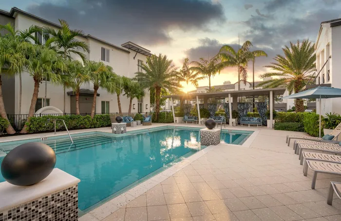 Pool lounge at our apartments for rent in Delray Beach, featuring outdoor chairs and a shade structure.