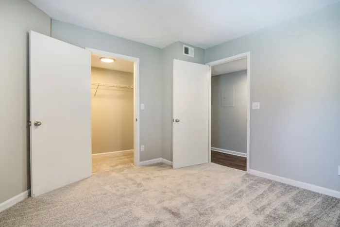 Empty bedroom at a 2-bedroom apartment in Bellevue, featuring carpeted flooring and a view of the closet and hallway.