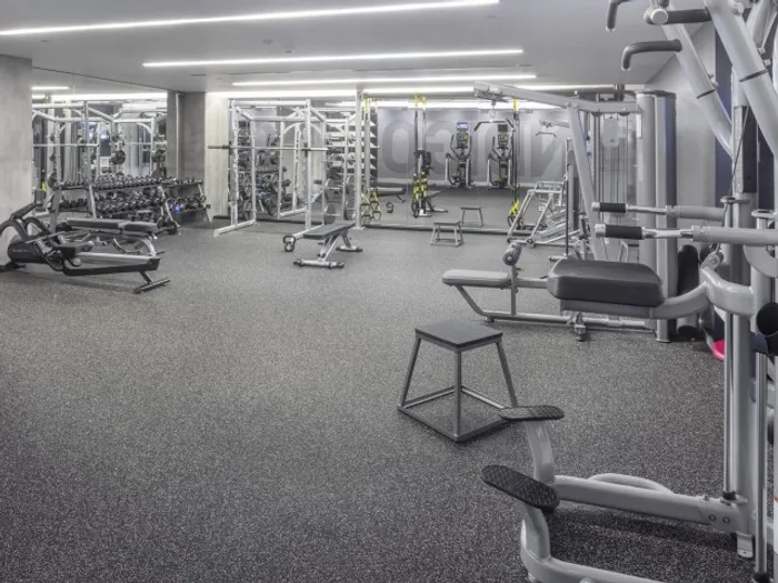 Gym at our apartments in Portland, OR, featuring exercise equipment, weights, and floor to ceiling mirrors.