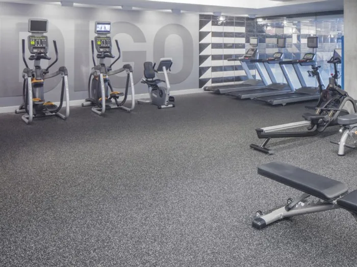 Gym at our apartments in Portland, OR, featuring exercise equipment, weights, and floor to ceiling mirrors.