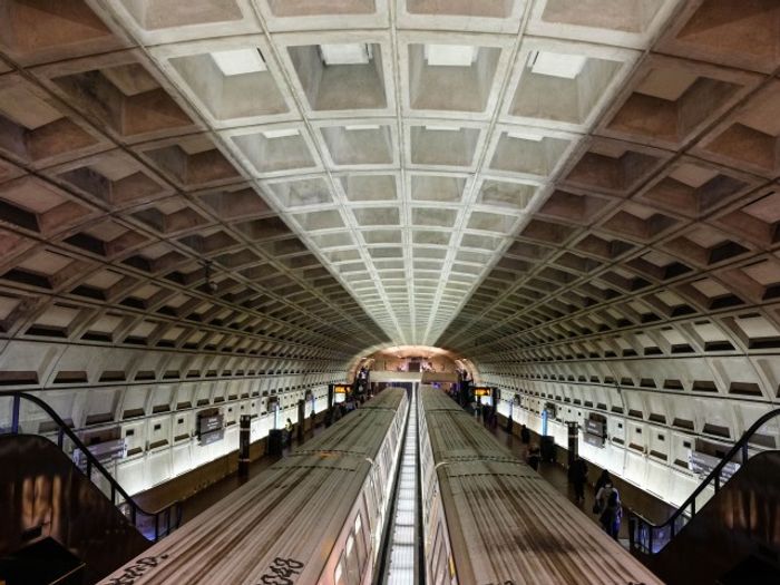 Trains in the station at our apartments for rent in Herndon, VA, featuring escalators and concrete roof slabs.
