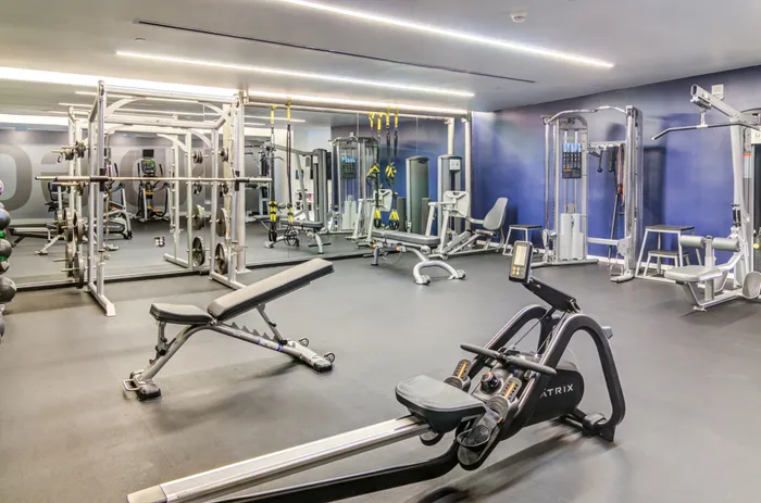 A large gym with exercise equipment and a mirror wall inside Indigo apartments in Portland.