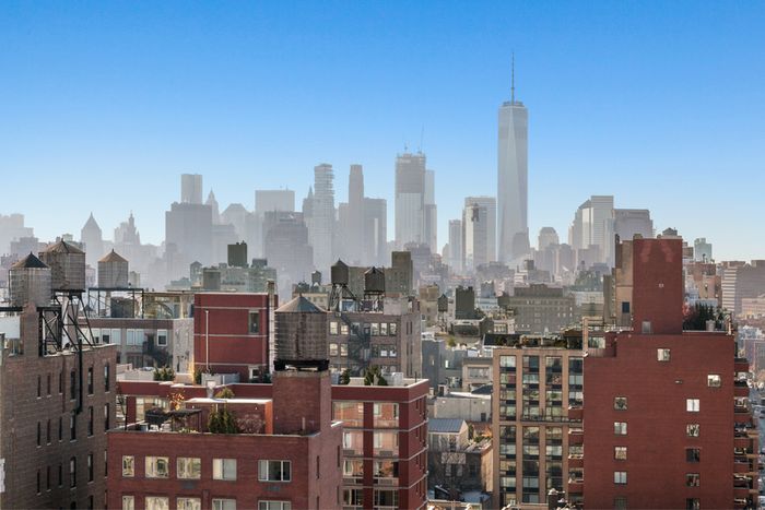 Photograph of the New York City skyline, featuring a view of brick buildings in the foreground and skyscrapers behind.