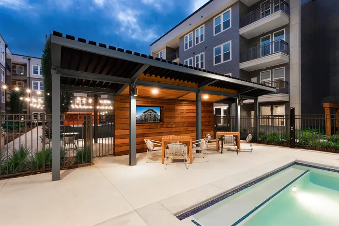 Pool lounge area at night with gazebo and tv