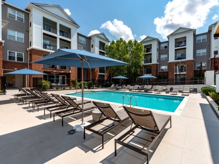 PoolThe pool area at our apartments for rent in Herndon, VA, featuring beach chairs, umbrellas, and a view of the apartments.