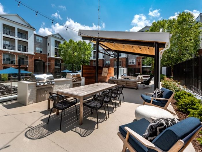 The outdoor lounge at our apartments for rent in Herndon, VA, featuring a shade structure, grill station, and outdoor chairs.