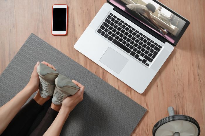 Someone doing a yoga class on a computer at our apartments for rent in Herndon, VA, featuring wood grain floor paneling.