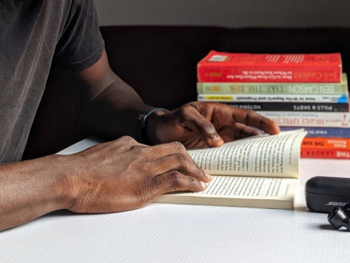 Someone reading a book at our apartments for rent in Herndon, VA, featuring a stack of books in the background.
