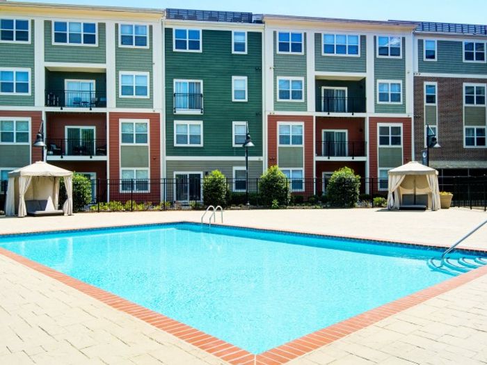 The pool area at our apartments for rent in Washington DC, featuring a covered beach chairs and a view of the apartments.