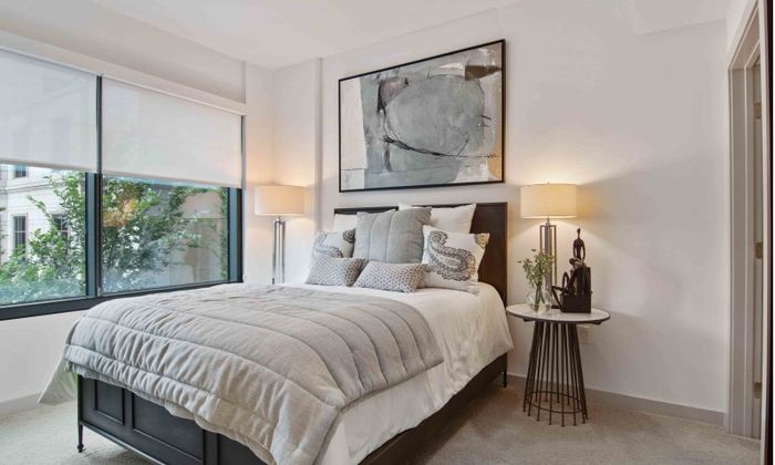 Model bedroom at our apartments in Atlanta, featuring carpeted floors, a large window, and elegant decor.