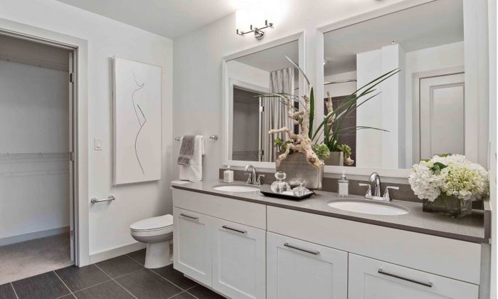 Model bathroom at our apartments in Atlanta, featuring tile flooring, grey countertops, and a view of the walk in closet.