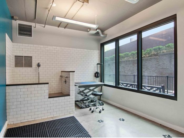 The pet washing station at our apartments for rent in Atlanta, GA featuring a tiled tub with a hose.