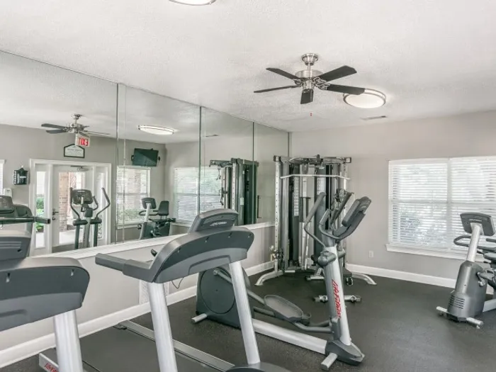 Fitness center featuring treadmills, cardio machines, a mirror, and weight machine