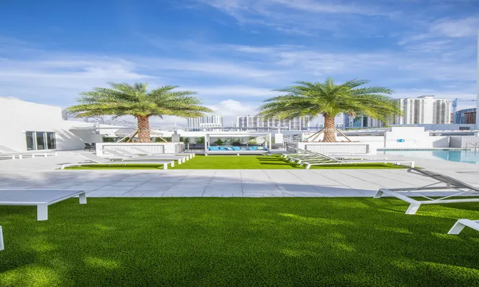 Outdoor lounge at our apartments for rent in Miami, featuring beach chairs, astroturf, and palm trees.