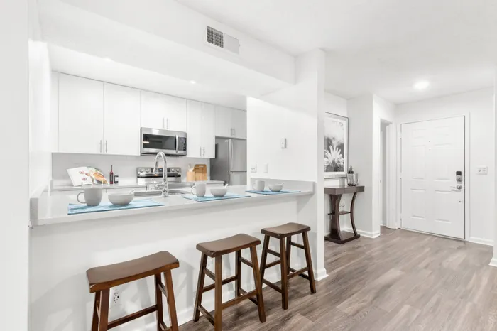 Luxury white kitchen with bar stools in a Clearwater apartment.