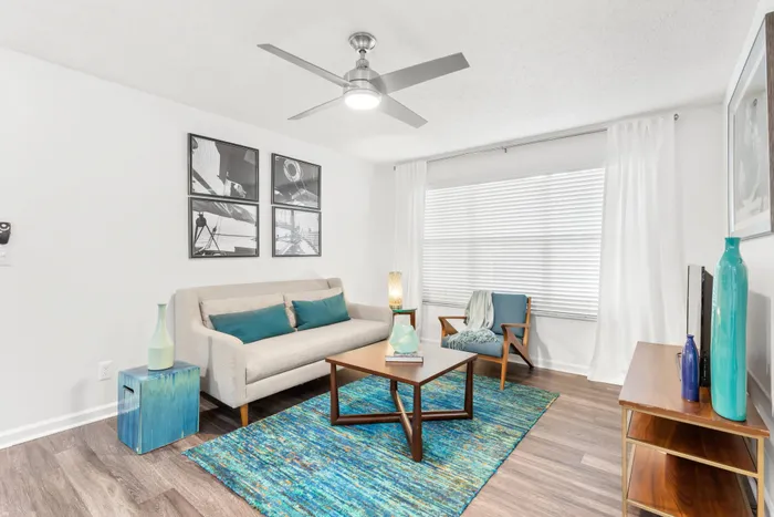 Model living room at our apartments in Clearwater, featuring wood laminate floors, a large window, and a flat screen TV.