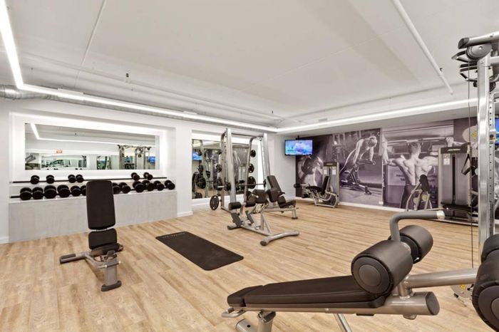 The fitness center at our apartments in Midtown Manhattan, featuring wood grain floor paneling and free weights.