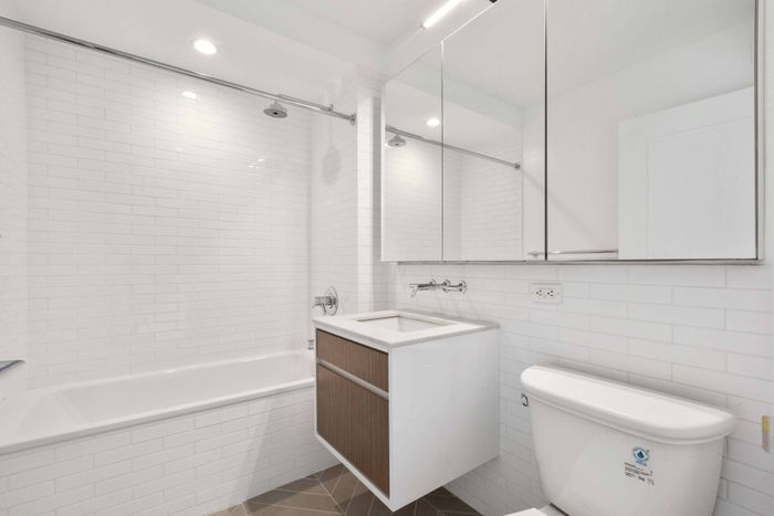 Bathroom with floating sink, large mirrors, and tub