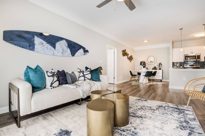 Model living room at our apartments for rent in Mooresville, NC, featuring wood grain floor paneling and a white couch.