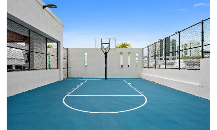 The basketball courts at our apartments in Brickell, featuring a blue clay court and a hoop with a glass backboard.