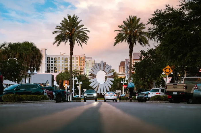 The streets of Clearwater, FL, near Avana City Park Apartments, featuring cars parked and a person riding a scooter.