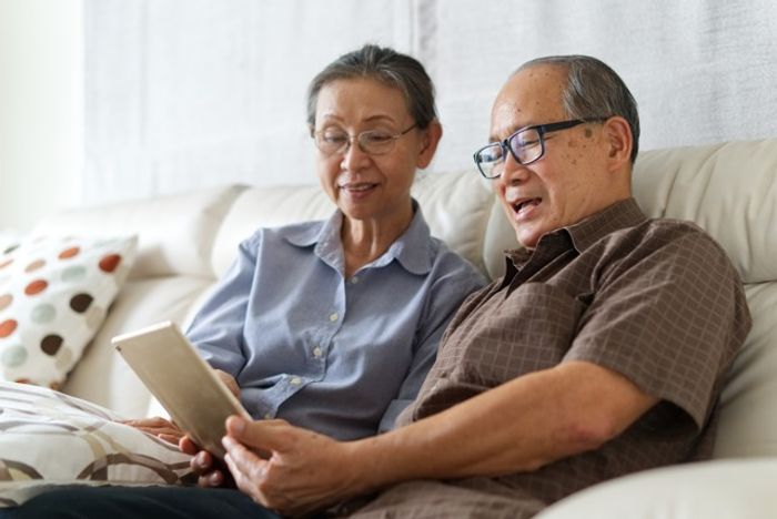 Two people sitting on a couch looking at an ipad in the living room of one of our apartments for rent in Herndon, VA.