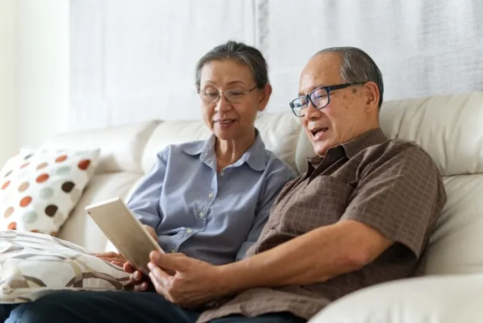Two elderly people sitting on a couch at our apartments for rent in Silver Spring, both are looking at an ipad.