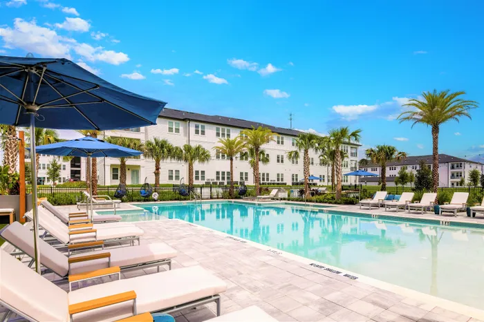 Pool courtyard with lounge chairs, umbrellas and palm trees
