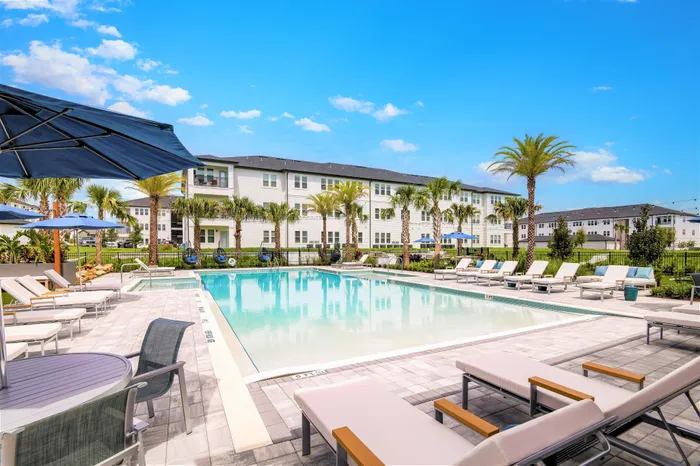 Stunning pool courtyard with lounge chairs, tables, palm trees