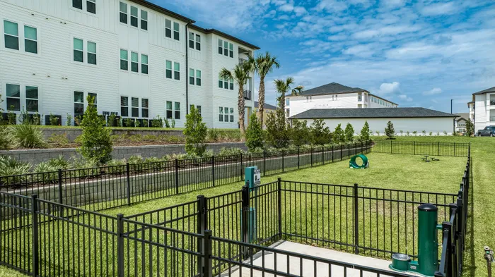 Large fenced in dog park with agility equipment and pet waste station