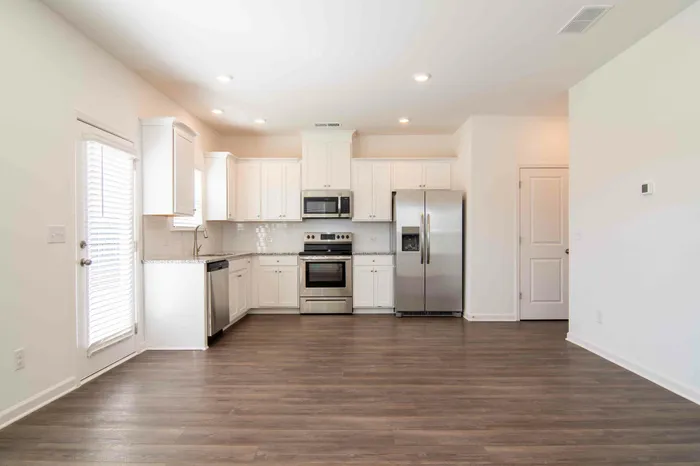 Open floor plan with kitchen and white cabinets