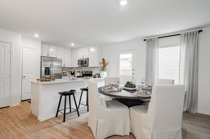dining room with swhite slipcovered chairs and black table looking into kitchen with island