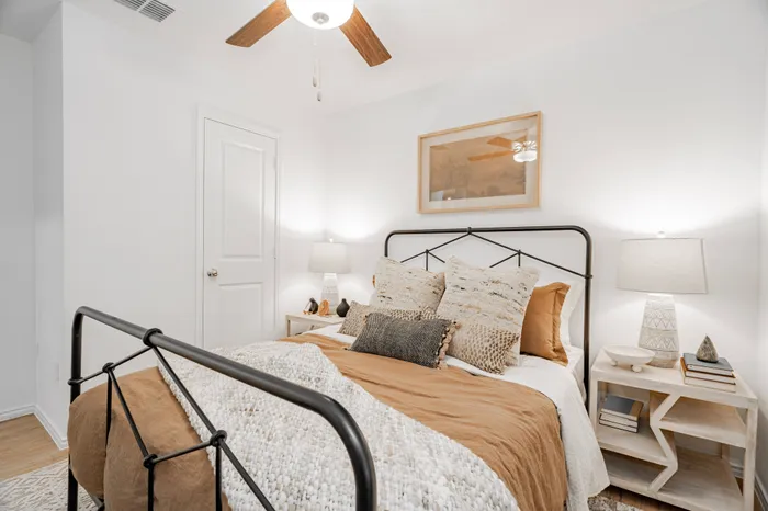 bedroom with iron bedframe and tan and white bedding