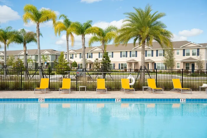pool with orange lounge chairs and homes behind
