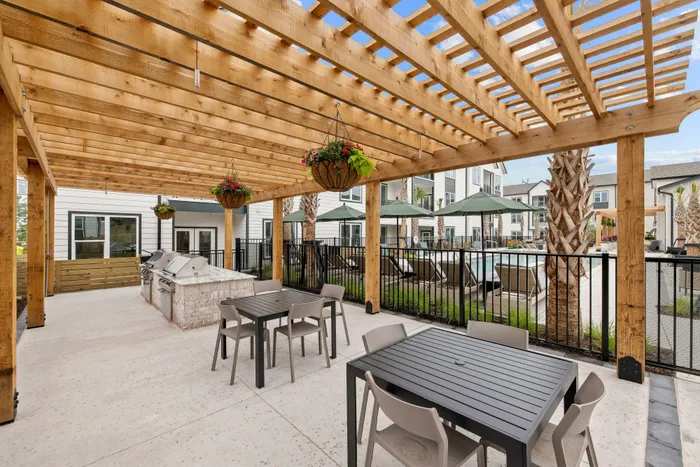 Outdoor grilling and dining area with pergola at apartment community