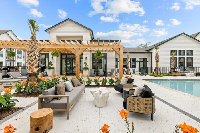 Outdoor patio seating area with pergola and landscaping at apartment community