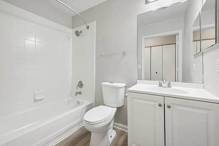 Bathroom with upgraded finishes, white cabinetry and a tub style shower
