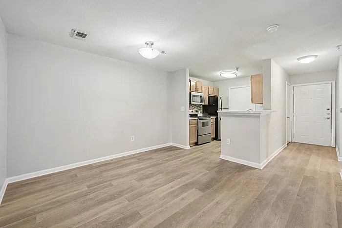 Large dining area with hardwood style flooring looking into the kitchen.