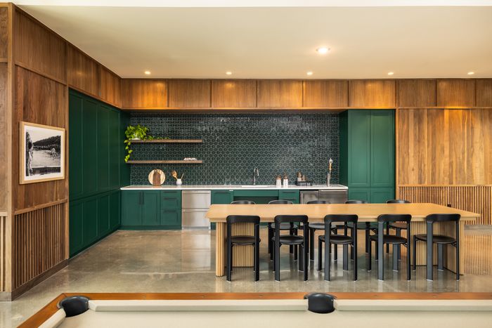Clubroom kitchen with green tile and bar seating at The Prado apartments in Del Valle, TX