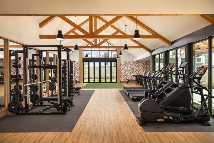 Fitness center with vaulted wood-beam ceiling at The Prado apartments in Del Valle, TX