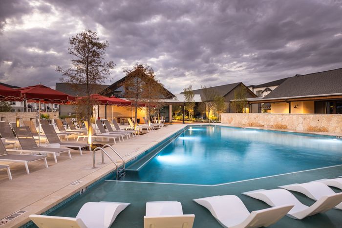 Pool with lounge chairs at sunset at The Prado apartments in Del Valle, TX