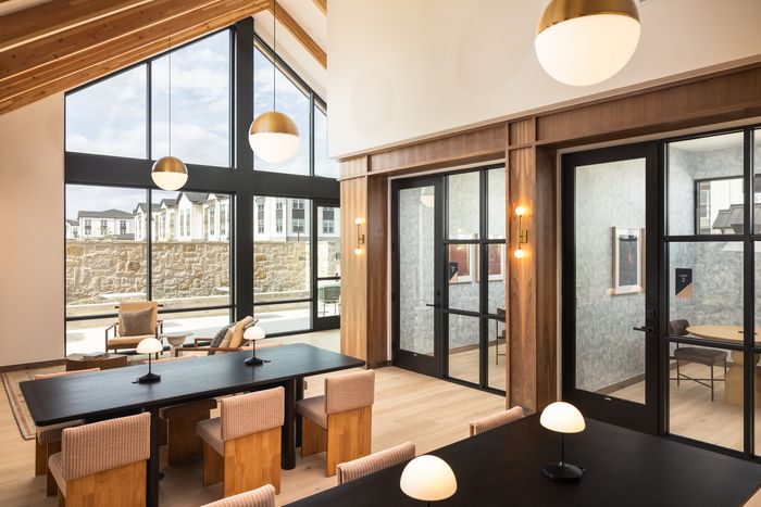 Co-working space with large table and pendant lights at The Prado apartments in Del Valle, TX