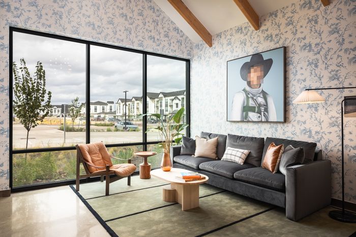 Co-working lounge with sofa and floor-to-ceiling windows at The Prado apartments in Del Valle, TX