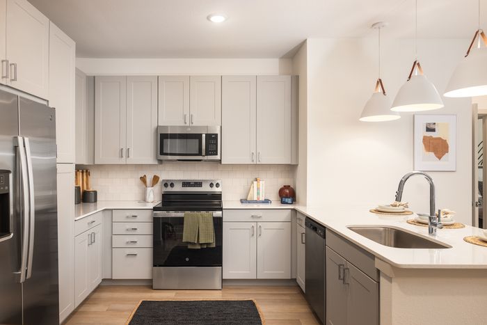 Apartment kitchen with white cabinets and stainless appliances at The Prado apartments in Del Valle, TX