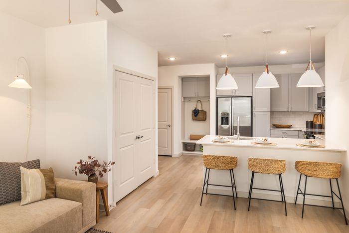 Apartment kitchen with white cabinets and island seating at The Prado apartments in Del Valle, TX